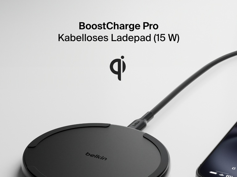 A black Belkin BoostCharge Pro Wireless Charging Pad 15W is shown in black with a connected charging cable, partially visible smartphone, and a Qi logo above the product name on a light background.