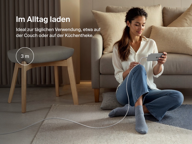 Woman sitting on the floor using a phone connected to the Belkin BoostCharge Pro USB-C to USB-C Braided Cable 240W, shown in a 3-meter (9.9 ft) length for everyday charging flexibility.