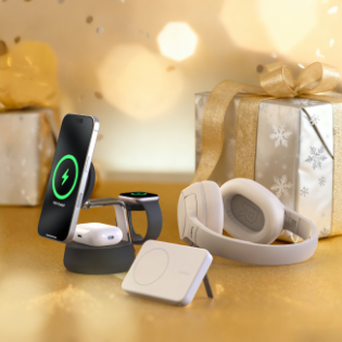 A festive scene featuring tech gifts, including a smartphone on a wireless charging stand, a smartwatch, wireless earbuds, a pair of over-ear headphones, and a portable charger, all displayed in front of wrapped presents with gold ribbons and snowflake-patterned paper against a warm golden background.