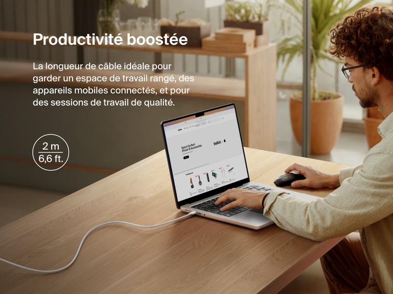 Man working at a desk with a laptop powered by the Belkin BoostCharge Pro USB-C to USB-C Braided Cable 240W, shown in a 2-meter (6.6 ft) length for an extended and clutter-free workspace.