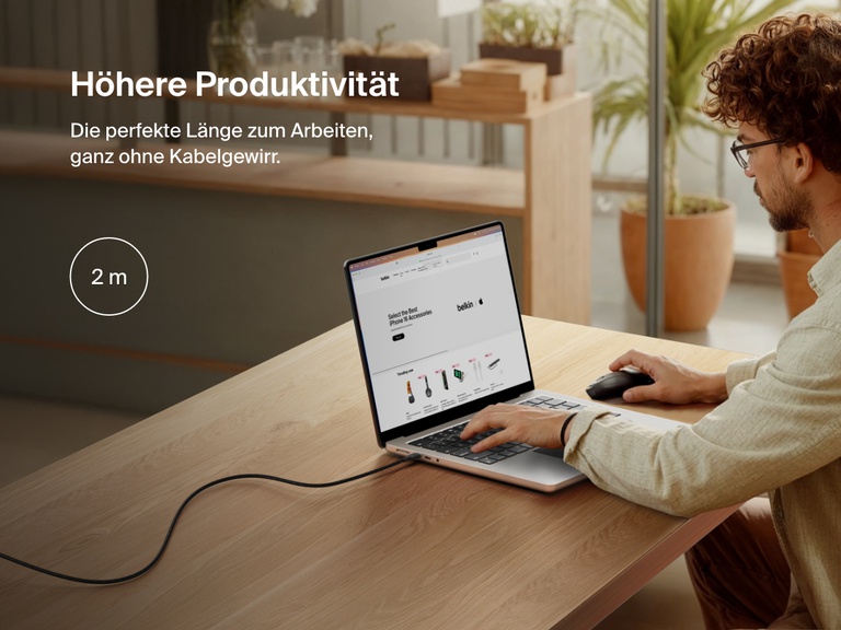 Man working at a desk with a laptop powered by the Belkin BoostCharge Pro USB-C to USB-C Braided Cable 240W, shown in a 2-meter (6.6 ft) length for an extended and clutter-free workspace.