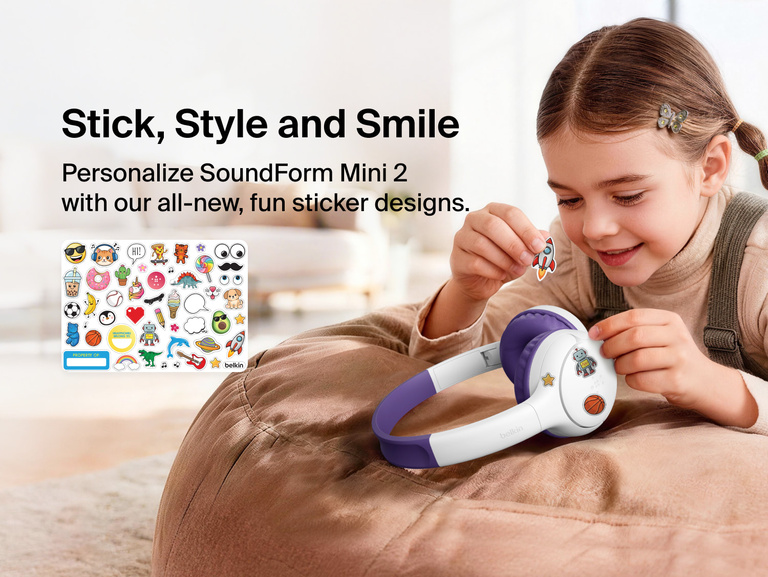 Child applying decorative stickers to the SoundForm Mini 2 Wireless On-Ear Headphones for Kids, with a full sticker sheet visible featuring playful emoji-style designs and a name label