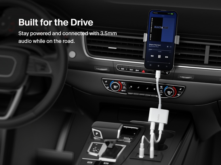 Belkin 3.5mm Audio + Charge RockStar™ keeps your iPhone powered and connected to a car stereo via 3.5mm audio while driving, shown mounted in a vehicle interior playing music.