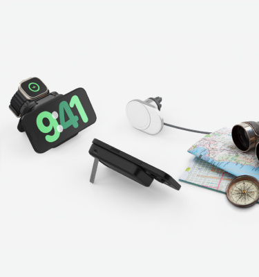 Travel bundle showing a charging station with a smartphone and smartwatch placed on it, along with a magnetic car charger and power bank. Nearby are travel items, including a map, compass, and binoculars, against a clean, white background.