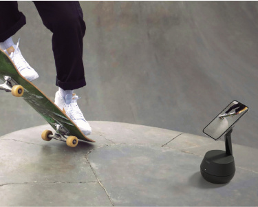 This image captures a skateboarder performing a trick in a skatepark while being recorded by a smartphone mounted on a sleek, black motion-tracking stand. The stand is positioned to follow the movement dynamically, emphasizing its ability to track and record action seamlessly. The background features a textured skatepark surface, highlighting an active and adventurous setting. This image captures a skateboarder performing a trick in a skatepark while being recorded by a smartphone mounted on a sleek, black motion-tracking stand. The stand is positioned to follow the movement dynamically, emphasizing its ability to track and record action seamlessly. The background features a textured skatepark surface, highlighting an active and adventurous setting.