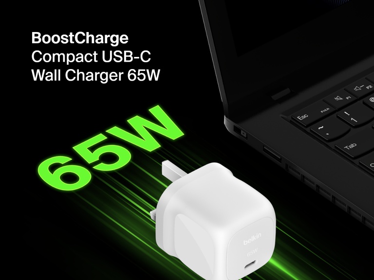 Angled image of the Belkin BoostCharge Compact USB-C Wall Charger 65W beside a laptop, highlighting its fast-charging capability with bold green "65W" text for emphasis.