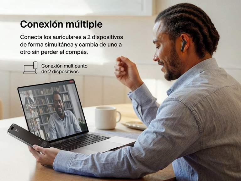 Imagen de un hombre usando unos auriculares ANC Belkin SoundForm Rhythm durante una videollamada realzando la conexión multipunto con 2 dispositivos para una conmutación fluida entre el portátil y un smartphone.