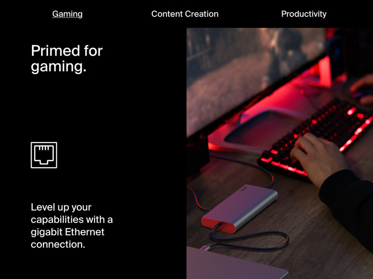 A user plays a PC game on a large monitor with a red-backlit keyboard, while the Belkin Connect Universal USB-C 8-in-1 Dual Display Core Hub provides a gigabit Ethernet connection for fast, stable internet.