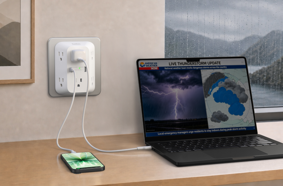 Belkin wall tap surge protector charging a laptop and smartphone from a wall outlet, delivering reliable surge protection during stormy weather.