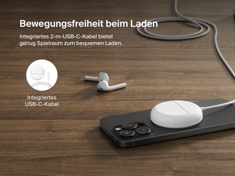 Ein weißes, magnetisches, kabelloses Belkin BoostCharge Pro-Ladegerät mit Qi2 und 15 Watt wird gezeigt, wie es ein iPhone auf einer Holzoberfläche mit einem integrierten 2-m-USB-C-Kabel für die flexible Positionierung lädt.