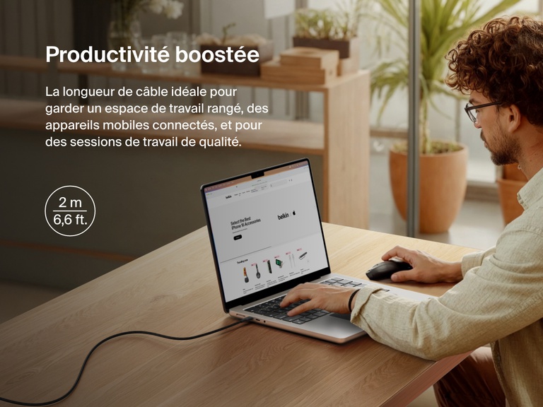 Man working at a desk with a laptop powered by the Belkin BoostCharge Pro USB-C to USB-C Braided Cable 240W, shown in a 2-meter (6.6 ft) length for an extended and clutter-free workspace.