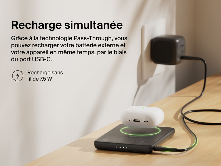 Belkin BoostCharge Slim Magnetic Power Bank 5K shown wirelessly charging earbuds while recharging via USB-C, demonstrating 7.5W pass-through charging functionality.