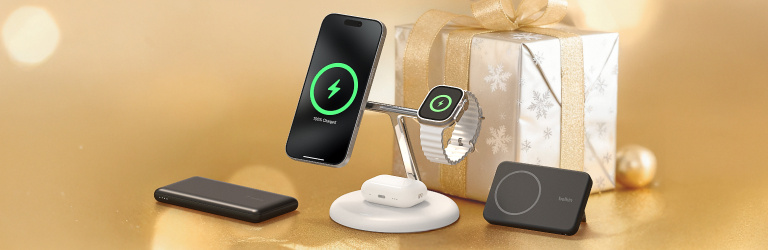 Holiday banner featuring Belkin best-selling tech gifts, including a wireless charging stand holding a phone, smartwatch, and earbuds, alongside a power bank and MagSafe charging pad, with a wrapped present in the background.