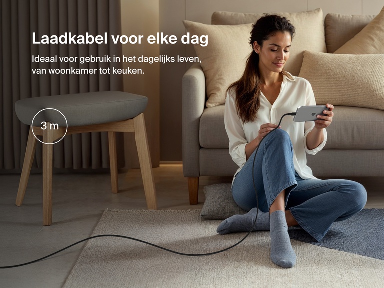 Woman sitting on the floor using a phone connected to the Belkin BoostCharge Pro USB-C to USB-C Braided Cable 240W, shown in a 3-meter (9.9 ft) length for everyday charging flexibility.