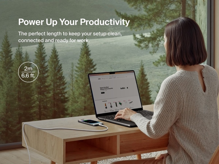 Belkin BoostCharge Pro USB-C Braided Cable with Lightning Connector in a 2m (6.6 ft.) length is shown powering an iPhone at a desk, offering extended reach and reliable charging for a productive workspace.