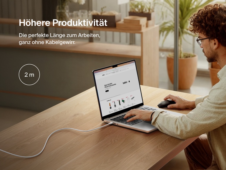 Man working at a desk with a laptop powered by the Belkin BoostCharge Pro USB-C to USB-C Braided Cable 240W, shown in a 2-meter (6.6 ft) length for an extended and clutter-free workspace.
