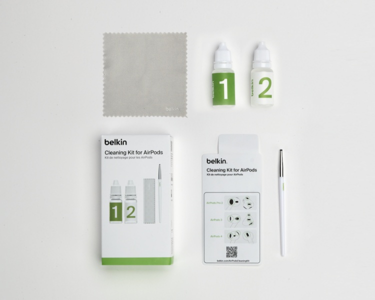 The image displays a complete cleaning kit for AirPods laid out neatly on a white surface. The kit includes a soft cleaning cloth, two bottles labeled "1" and "2" for a two-step cleaning process, a cleaning tool or pen, an instruction card with diagrams, and the product's packaging box labeled "Belkin Cleaning Kit for AirPods." The arrangement highlights the contents of the kit and emphasizes its step-by-step cleaning approach.