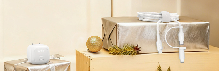 Holiday banner with Belkin tech stocking stuffers displayed on wrapped presents, including a white 20W wall charger and a white charging cable, set against a festive background with ornaments and greenery.