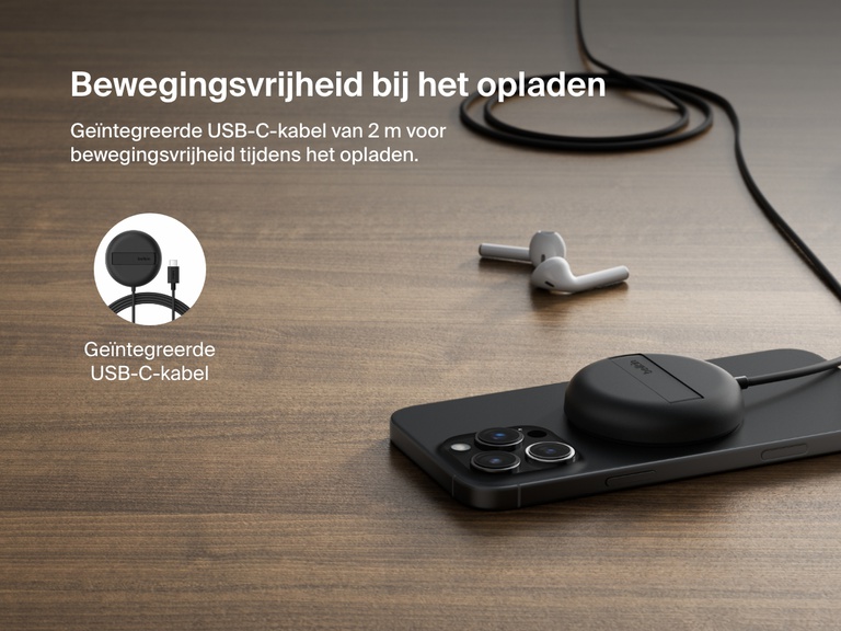 Afbeelding van een zwart Belkin BoostCharge Pro magnetisch draadloos laadstation met Qi2 (15 W) die een iPhone oplaadt op een houten oppervlak, met een vaste USB-C-kabel van 2 meter voor flexibel gebruik.