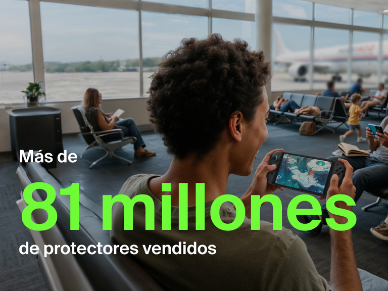 Una persona joven sonríe mientras juega en una Nintendo Switch 2 en la zona de embarque de un aeropuerto. En el fondo, otros viajeros están sentados, leyendo o usando sus móviles y por la ventana se ve un avión fuera. Texto verde de gran tamaño en frontal de la imagen dice «Más de 81 millones», y un texto blanco abajo afirma «protectores de pantalla vendidos», resaltando la popularidad del producto.