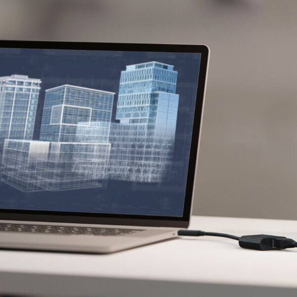 Laptop displaying a 3D architectural model of buildings, connected to a Belkin Ethernet adapter for enhanced data transfer and reliable connectivity.