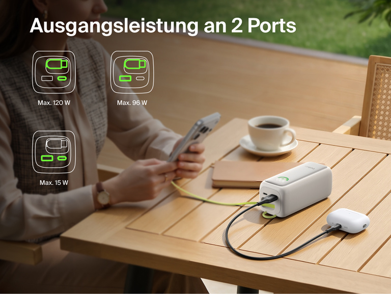 UltraCharge Powerbank 22K mit einziehbarem Kabel, die an einem Tisch ein Smartphone und ein Ladecase f&uuml;r In-Ear-Kopfh&ouml;rer &uuml;ber zwei Anschl&uuml;sse gleichzeitig l&auml;dt, mit Symbolen f&uuml;r die verf&uuml;gbaren Leistungskombinationen.