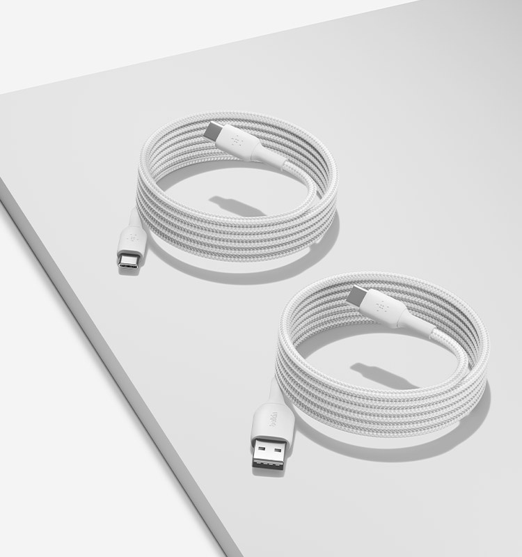 Two white Belkin braided cables, a USB-C to USB-A Cable 15W and a USB-C to USB-C Cable 60W, are coiled neatly on a light gray surface.