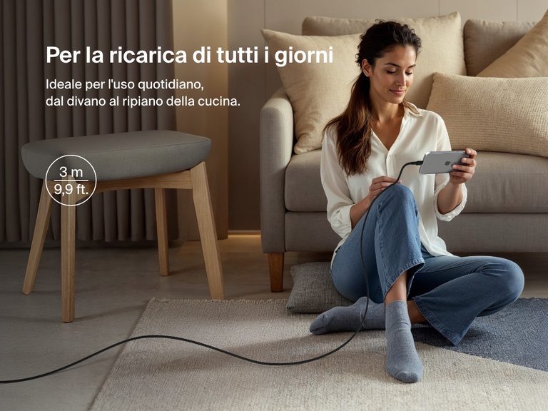 Woman sitting on the floor using a phone connected to the Belkin BoostCharge Pro USB-C to USB-C Braided Cable 240W, shown in a 3-meter (9.9 ft) length for everyday charging flexibility.