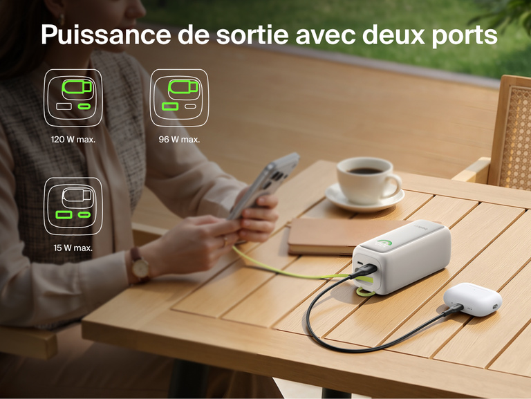 Image d'une batterie externe 22K UltraCharge avec c&acirc;ble r&eacute;tractable rechargeant un t&eacute;l&eacute;phone et un &eacute;tui d'&eacute;couteurs sur une table via deux&nbsp;ports, avec des ic&ocirc;nes indiquant les diff&eacute;rentes combinaisons de puissance disponibles.