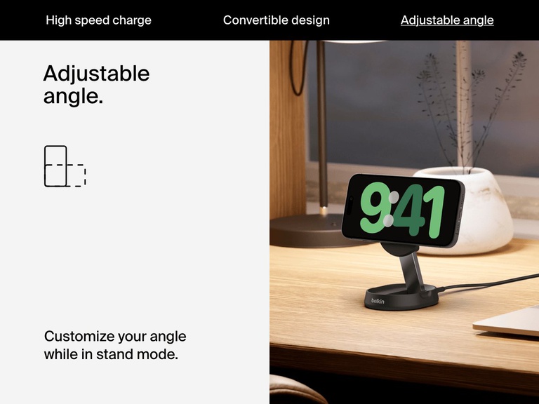 A black Belkin BoostCharge Pro Convertible Magnetic Wireless Charging Stand with Qi2 15W holds a horizontally oriented iPhone on a desk, illustrating its adjustable viewing angle in stand mode.