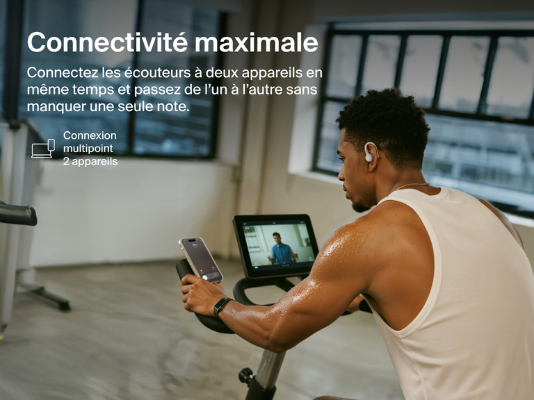 Belkin SoundForm ActiveFit Wireless Earbuds with multipoint 2-device connection, shown on a man using them while cycling on a stationary bike.
