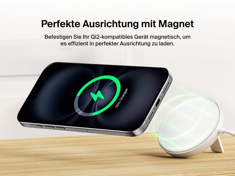 Ein weißes, magnetisches, kabelloses Belkin BoostCharge Pro-Ladegerät mit Qi2 und 15 Watt wird gezeigt, wie es magnetisch auf das iPhone passt und so effizient und kabellos auf einer Holzoberfläche lädt. 