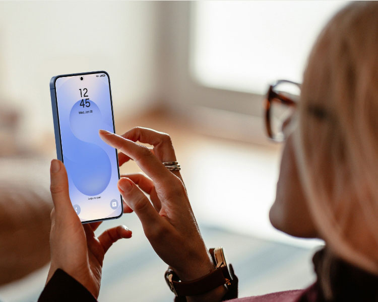 This image shows a person reclining on a couch while using a smartphone. The focus is on the phone screen, which is vibrant and clear, suggesting the use of a high-quality screen protector. The person appears relaxed, emphasizing comfort and usability. The blurred background and natural lighting create a warm, casual atmosphere, highlighting the device and its screen clarity.