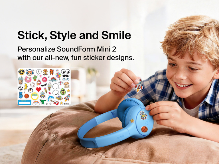 Child applying decorative stickers to the SoundForm Mini 2 Wireless On-Ear Headphones for Kids, with a full sticker sheet visible featuring playful emoji-style designs and a name label