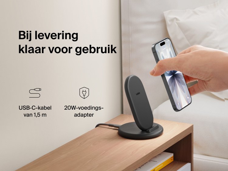 Belkin BoostCharge Wireless Charging Stand 15W shown on a bedside table with smartphone, includes 5ft USB-C cable and 20W power adapter for immediate charging out of the box.
