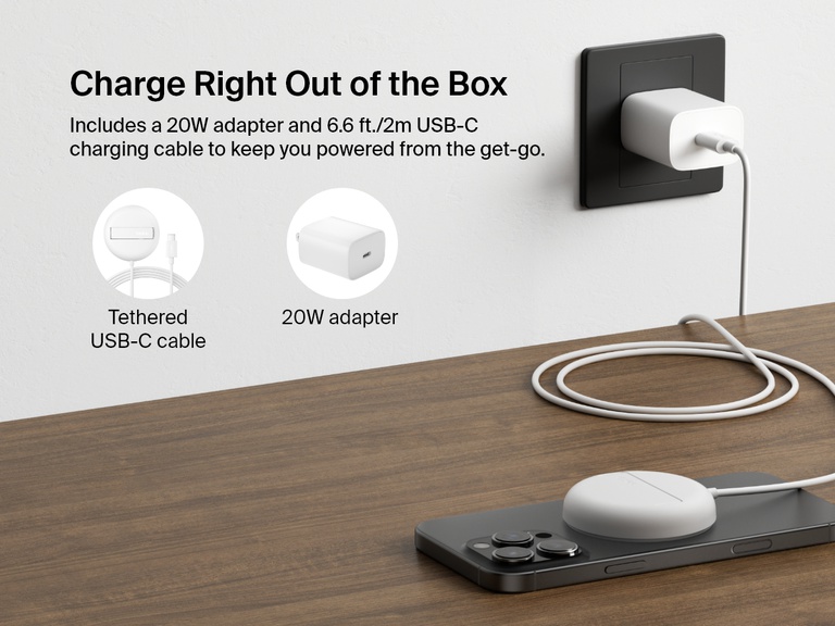 A white Belkin BoostCharge Pro Magnetic Wireless Charging Pad with Qi2 15W is shown charging an iPhone on a desk, highlighting its included 20W power adapter and 6.6ft/2m tethered USB-C cable for out-of-the-box convenience.