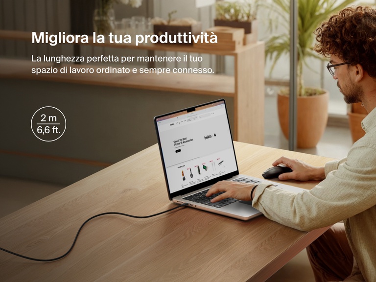 Man working at a desk with a laptop powered by the Belkin BoostCharge Pro USB-C to USB-C Braided Cable 240W, shown in a 2-meter (6.6 ft) length for an extended and clutter-free workspace.