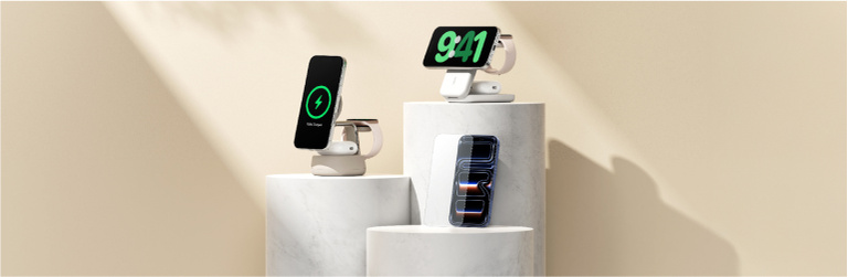 Three iPhones displayed on Belkin charging stands, two showing charging indicators (100% charged and 9:41), and one with a modern abstract wallpaper, set on white marble pedestals against a beige background.