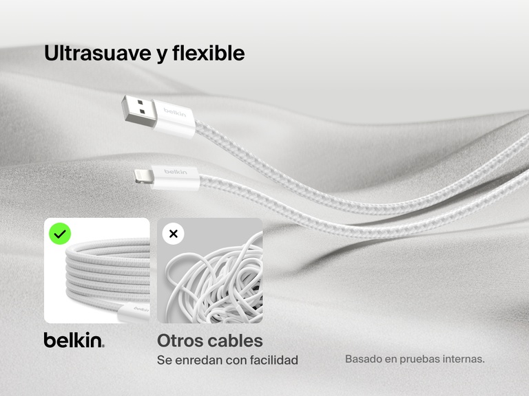 Cable Belkin BoostCharge USB-A con conector Lightning mostrado sobre un tejido suave, destacando su diseño trenzado ultraflexible antienredos en comparación con los cables estándar que se enredan con facilidad.