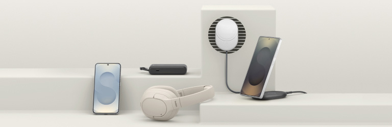 A sleek display of Samsung Galaxy S25-compatible accessories, including a screen protector, headphones, chargers, and wireless charging pads, arranged on minimalist geometric platforms.