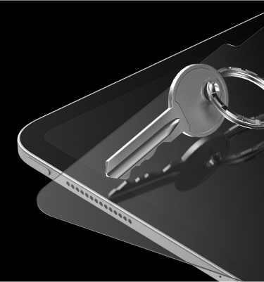 A close-up view of a tablet with a key placed on its screen, demonstrating the durability and scratch resistance of the tablet's tempered glass screen protector. The image features a sleek, modern design with a black background, highlighting the tablet's edge and speaker grill.