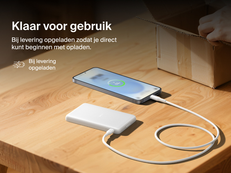 Belkin BoostCharge Slim Magnetic Power Bank 5K shown charging a smartphone on a table, highlighting its precharged battery ready for instant use out of the box.