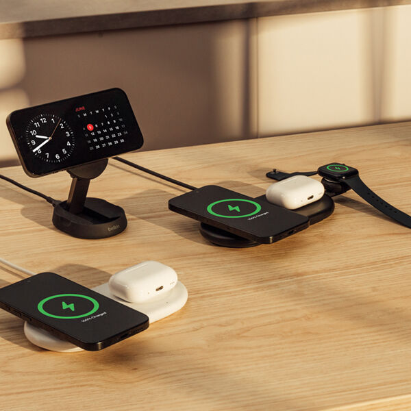 Belkin wireless charging setup featuring multiple devices, including smartphones, earbuds, and a smartwatch, all powered by Qi-enabled charging pads and stands.