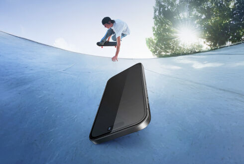 스케이트파크 경사로에 강화유리를 붙인 스마트폰이 놓여 있고, 배경에서는 스케이트보더가 트릭을 선보이고 있습니다. 이는 내구성과 낙하 보호 기능을 상징합니다.