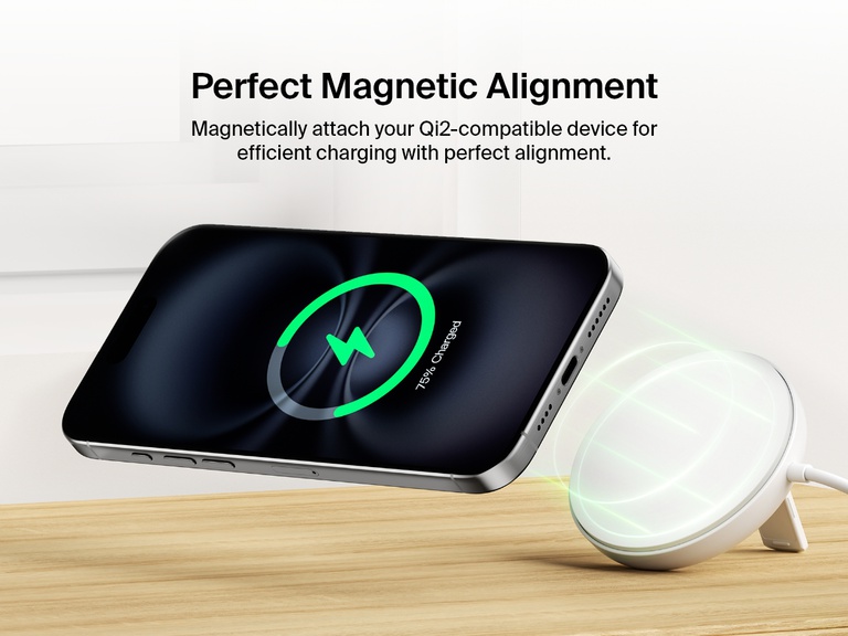 木製のテーブルの上で、Belkin BoostCharge Proマグネット式ワイヤレス充電パッド（Qi2 15W、ホワイト）をマグネットでiPhoneと正確に位置合わせし、効率的にワイヤレス充電を行う様子が示されています。