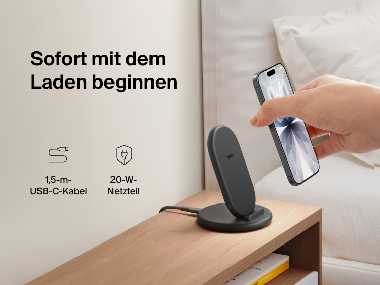 Belkin BoostCharge Wireless Charging Stand 15W shown on a bedside table with smartphone, includes 5ft USB-C cable and 20W power adapter for immediate charging out of the box.