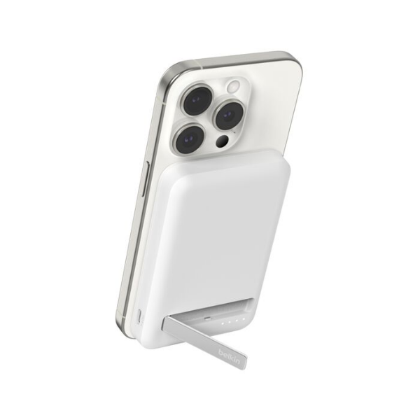 A white iPhone attached to a Belkin magnetic wireless power bank with a built-in foldable kickstand extended for support.