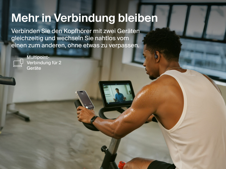 Belkin SoundForm ActiveFit Wireless Earbuds with multipoint 2-device connection, shown on a man using them while cycling on a stationary bike.
