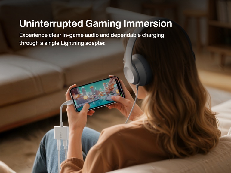 Woman gaming on her iPhone while using the Belkin 3.5mm Audio + Charge RockStar™ adapter to enjoy immersive audio with wired headphones and uninterrupted charging via the Lightning port.