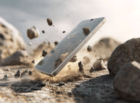 Smartphone suspended above rocky ground as stones and debris scatter around it, illustrating durability and resistance to impacts.